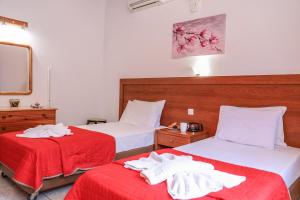 a bedroom with two beds with red sheets at VILLA MITZELOS in Skiathos