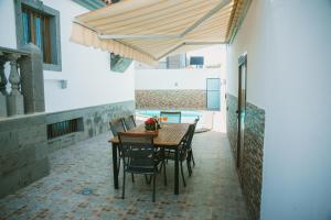 una mesa de madera y sillas bajo una sombrilla de madera en Villa Cervantes Sonnenland con piscina privada climatizada en Maspalomas