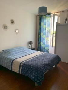 1 dormitorio con 1 cama con manta azul y ventana en La maisonnée de Chambord, en Crouy-sur-Cosson