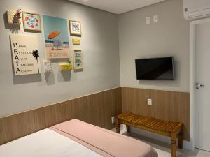 1 dormitorio con 1 cama y TV en la pared en Guarajuba Summer Flat Melhor localização de Guarajuba e melhores Flats Beira Mar de Guarajuba Dispomos de 4 flats decorados no mesmo condomínio Aqui você não precisa de carro para nada Faça tudo à pé en Guarajuba