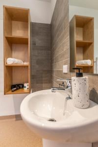 La salle de bains est pourvue d'un lavabo blanc et d'un miroir. dans l'établissement Camp Waipu Cove, à Waipu
