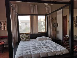 uma cama de dossel num quarto com uma grande janela em Daffodils em Ajman