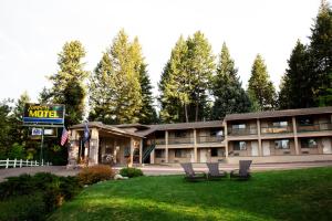 a hotel with three chairs sitting in the grass at Timbers Motel in Bigfork