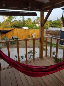 een hangmat op een veranda met een houten terras bij ZENALIZES bungalow calme et confortable in Le Moule