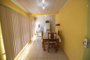 Habitación con mesa y cocina con paredes amarillas. en Pousada Dalmar, en Penha