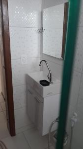 een witte badkamer met een wastafel en een spiegel bij Excelente apto em Caiobá a 3 quadras da praia! in Matinhos