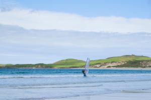 a person is windsurfing in the water on the beach at Durness Youth Hostel in Durness