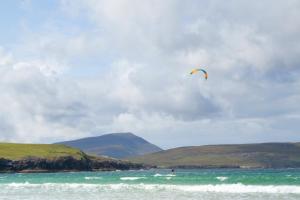 a person is flying a kite over the ocean at Durness Youth Hostel in Durness