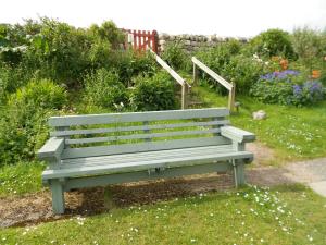 a green bench sitting in a garden with flowers at Durness Youth Hostel in Durness