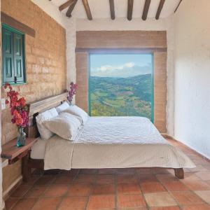 een slaapkamer met een bed en een groot raam bij Macúa in Chipatá