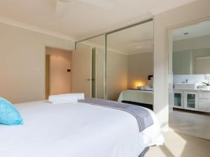 - une chambre avec un lit blanc et un miroir dans l'établissement Shore To Please, à Kiama