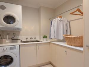 een keuken met een wasmachine en een wastafel bij Shore To Please in Kiama