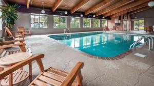una piscina en un edificio con sillas y mesas en Best Western Plus North Canton Inn & Suites, en North Canton