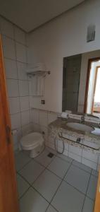 a bathroom with a toilet and a sink and a mirror at APARTAMENTO ÁGUAS DA SERRA - 005b in Rio Quente
