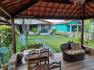 un patio con sofá y una silla en una terraza de madera en Parque dos Coqueiros - Casa, en Maragogi