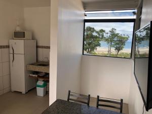 Elle comprend une petite cuisine avec un réfrigérateur et une fenêtre. dans l'établissement Apartamento Ilha do Coral, à Palhoça
