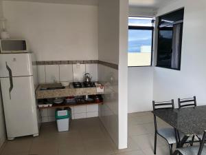 a kitchen with a refrigerator and a table and a window at Apartamento Ilha do Coral in Palhoça