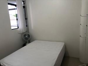 um pequeno quarto com uma cama branca e uma janela em Apartamento Ilha do Coral em Palhoça