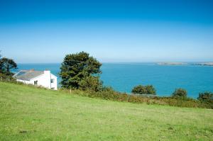 a white house on a hill next to the ocean at YHA Poppit Sands in Cardigan