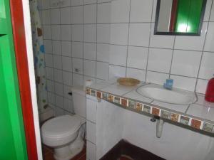 a small bathroom with a toilet and a sink at Hostal Vacaciones Nicas in León