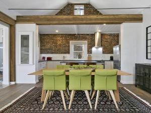 a kitchen with a wooden table and green chairs at Old Bank Stables in Moss Vale
