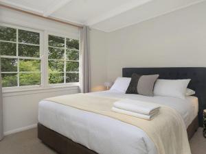 a bedroom with a large bed with two windows at Que Sera in Bowral