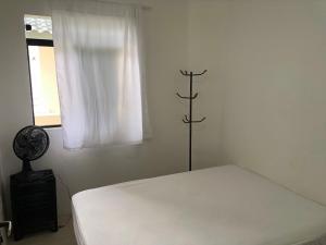 ein weißes Schlafzimmer mit einem Bett und einem Fenster in der Unterkunft Apartamento Ilhas Três Irmãs in Palhoça
