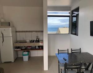 eine Küche mit einem Kühlschrank, einem Tisch und einem Fenster in der Unterkunft Apartamento Ilhas Três Irmãs in Palhoça