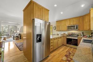 a kitchen with wooden cabinets and a stainless steel refrigerator at Gateway to the Wildside Townhouse in Estes Park +32 photos