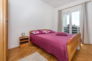 - une chambre avec un lit doté de draps violets et une fenêtre dans l'établissement Apartments Baldo, à Vodice 45 autres photos