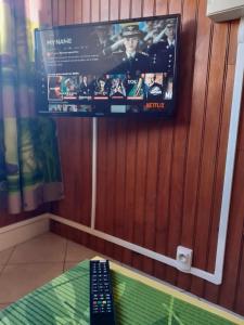 a tv hanging on a wall with a remote control at Auberge du Cap in Cilaos