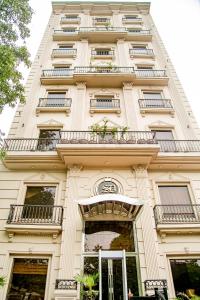 a tall white building with windows and balconies at Saffron D'or Hotels in Lahore