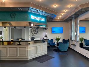 a waiting room with blue chairs and a reception desk at E&D Hotel Rodgau in Rodgau