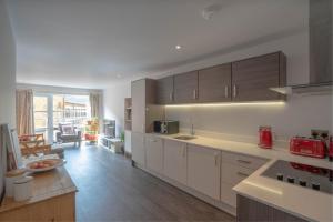 a kitchen with white cabinets and a living room at Gorgeous Spacious 2 Bed 2 Bath Apartment in Leicester