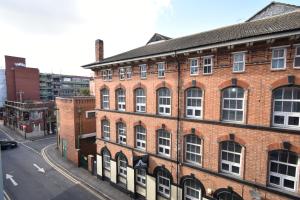 un vecchio edificio in mattoni rossi su una strada di città di Gorgeous Spacious 2 Bed 2 Bath Apartment a Leicester