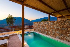 Una casa con piscina y montañas al fondo. en Galini Luxury Homes, en Saktoúria