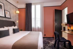 um quarto de hotel com uma cama grande e uma cadeira em Hôtel Palais De Chaillot em Paris