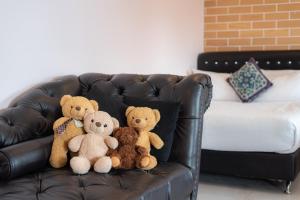 three teddy bears sitting on a leather couch at Little Bear's Home in Chiang Mai