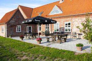 a patio with picnic tables and an umbrella in front of a building at Ballum Slusekro in Ballum