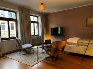a bedroom with a bed and a tv and chairs at elegant and relaxing nordstadt studio in Hannover