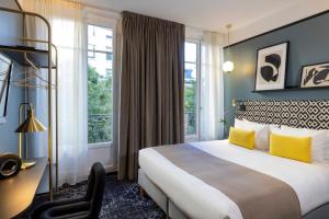 um quarto de hotel com uma cama, uma secretária e janelas em Hôtel Palais De Chaillot em Paris