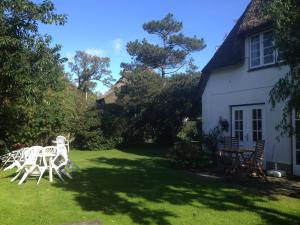 a yard with white chairs and a house at Blaue Stube in Nieblum