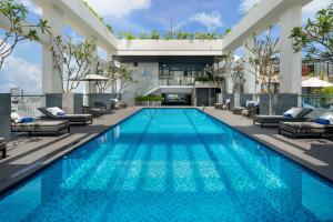 a swimming pool with lounge chairs and a building at Paris Deli Danang Beach Hotel in Danang