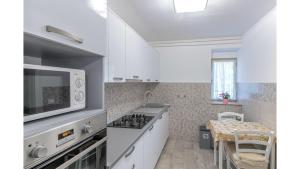 uma cozinha com armários brancos e um forno com placa de fogão em Apartment Erin em Umag