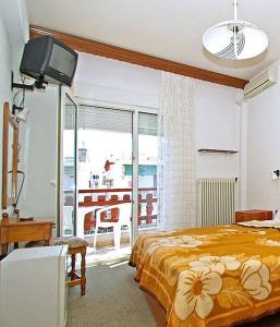 1 dormitorio con cama, TV y balcón en Hotel Helios en Paralia Katerinis