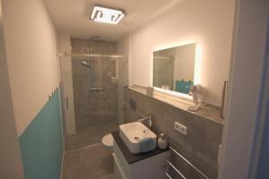 a bathroom with a sink and a shower with a mirror at Ferienwohnung Hegaublüte in Engen +9 photos