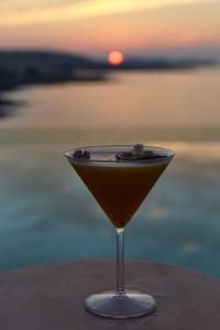a martini glass sitting on a table with a sunset in the background at Can Salia in San Antonio Bay