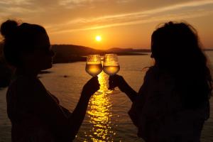 two women holding wine glasses in front of a sunset at Can Salia in San Antonio Bay