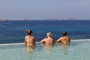 three women sitting in a swimming pool overlooking the ocean at Can Salia in San Antonio Bay