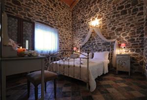 a bedroom with a bed and a stone wall at Palaeopoli Villas in Avlemonas